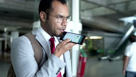 Businessman-with-backpack-talking-by-smartphone-in-airport